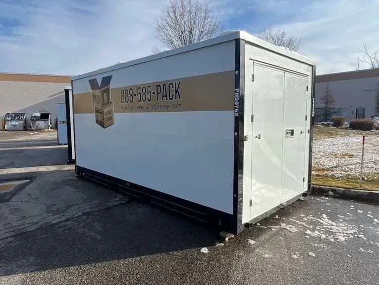 A container in a commercial lot, snow banked along the edge of the pavement.