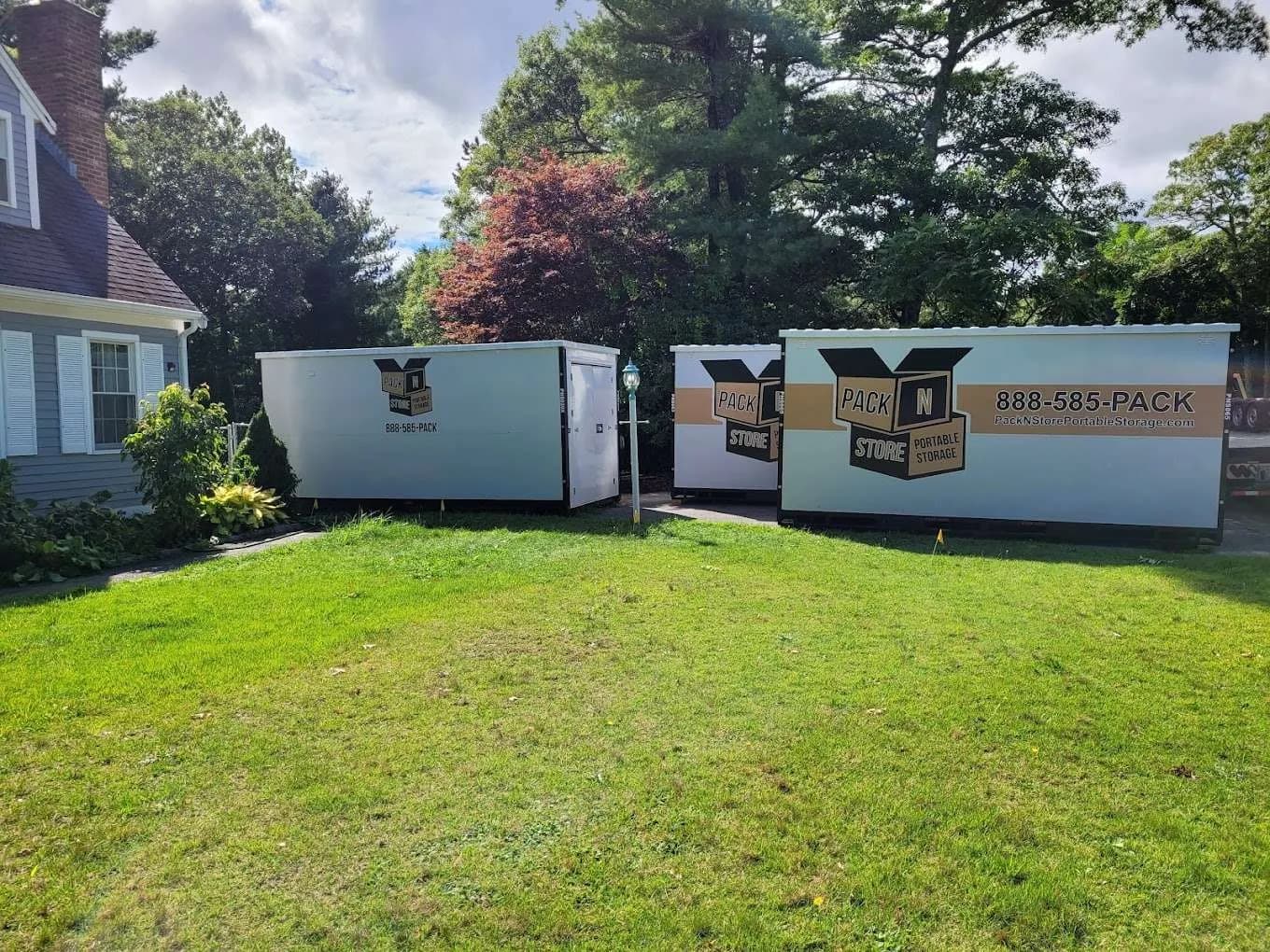 Three containers on a lawn beside a house, the delivery truck still on site.