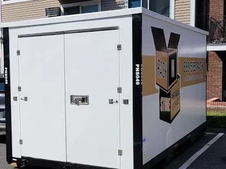 A container placed across parking spaces at a three-storey apartment building.