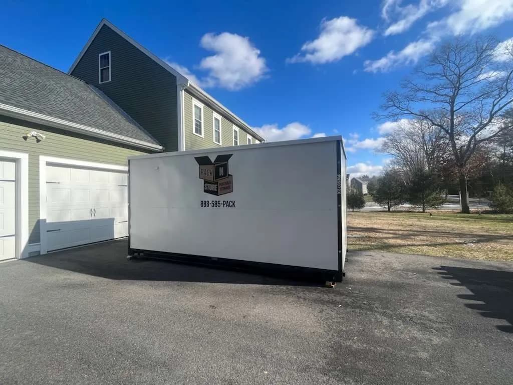 A container on a driveway against the garage apron, using the full width of the drive.