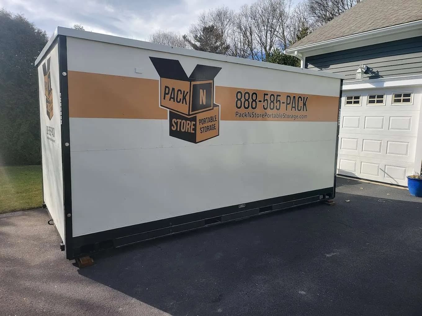 A container hard against a garage apron, planks under both corners.